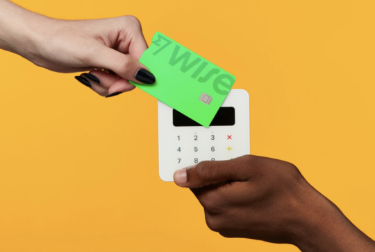Wise credit card being held against a payment machine